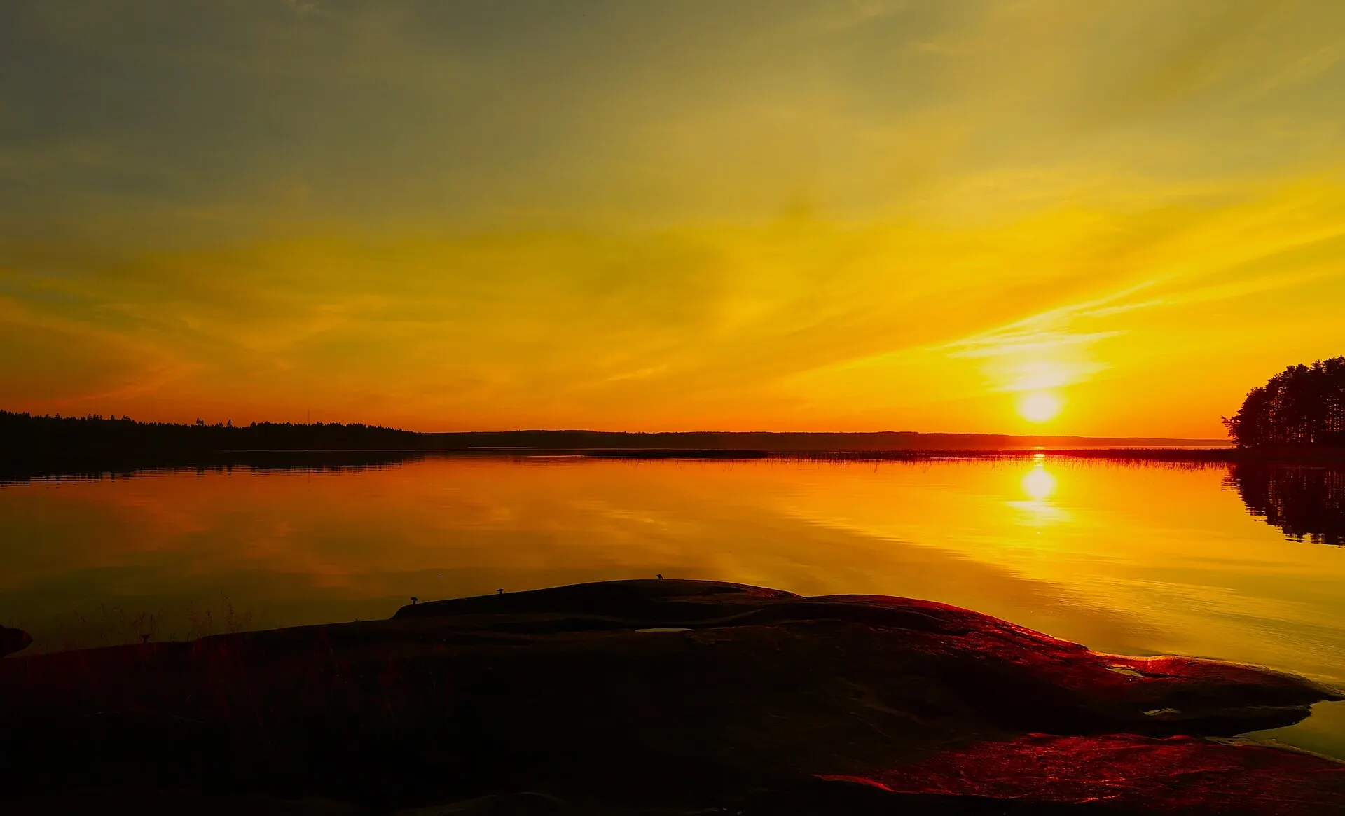 Auringonlasku järvimaiseman yllä